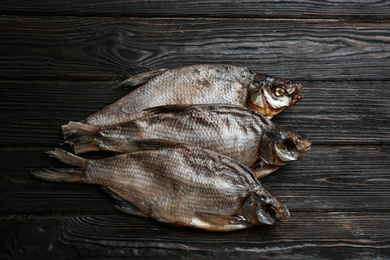 Photo of Tasty dried fish on black wooden table, flat lay