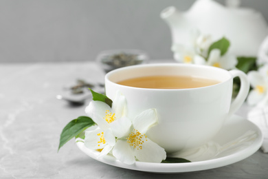 Cup of tea and fresh jasmine flowers on light grey marble table