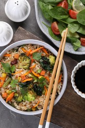 Photo of Tasty fried rice with vegetables served on grey table, flat lay