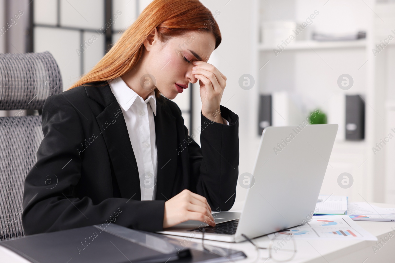 Photo of Woman suffering from headache at workplace in office