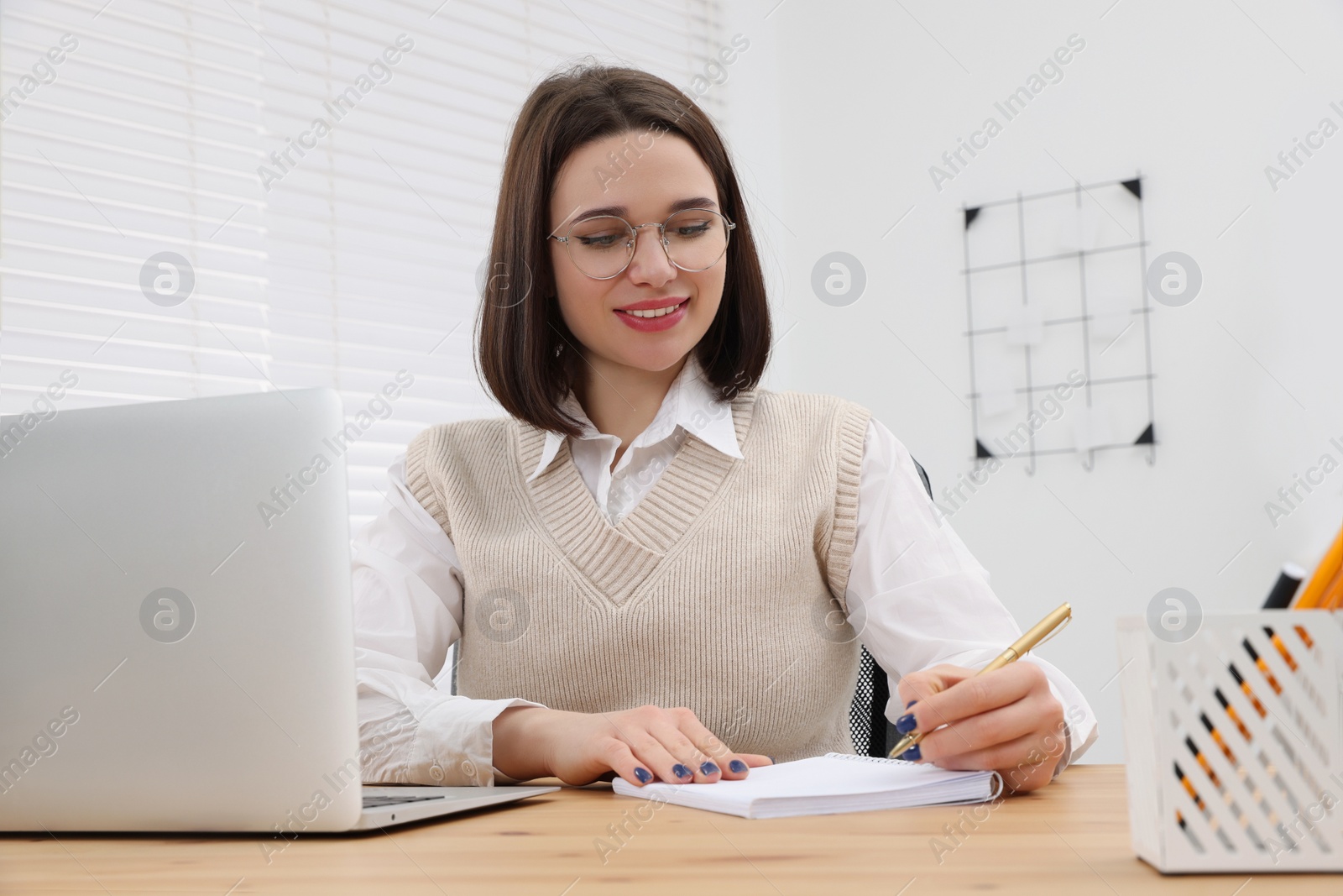 Photo of Happy young intern working at table in modern office