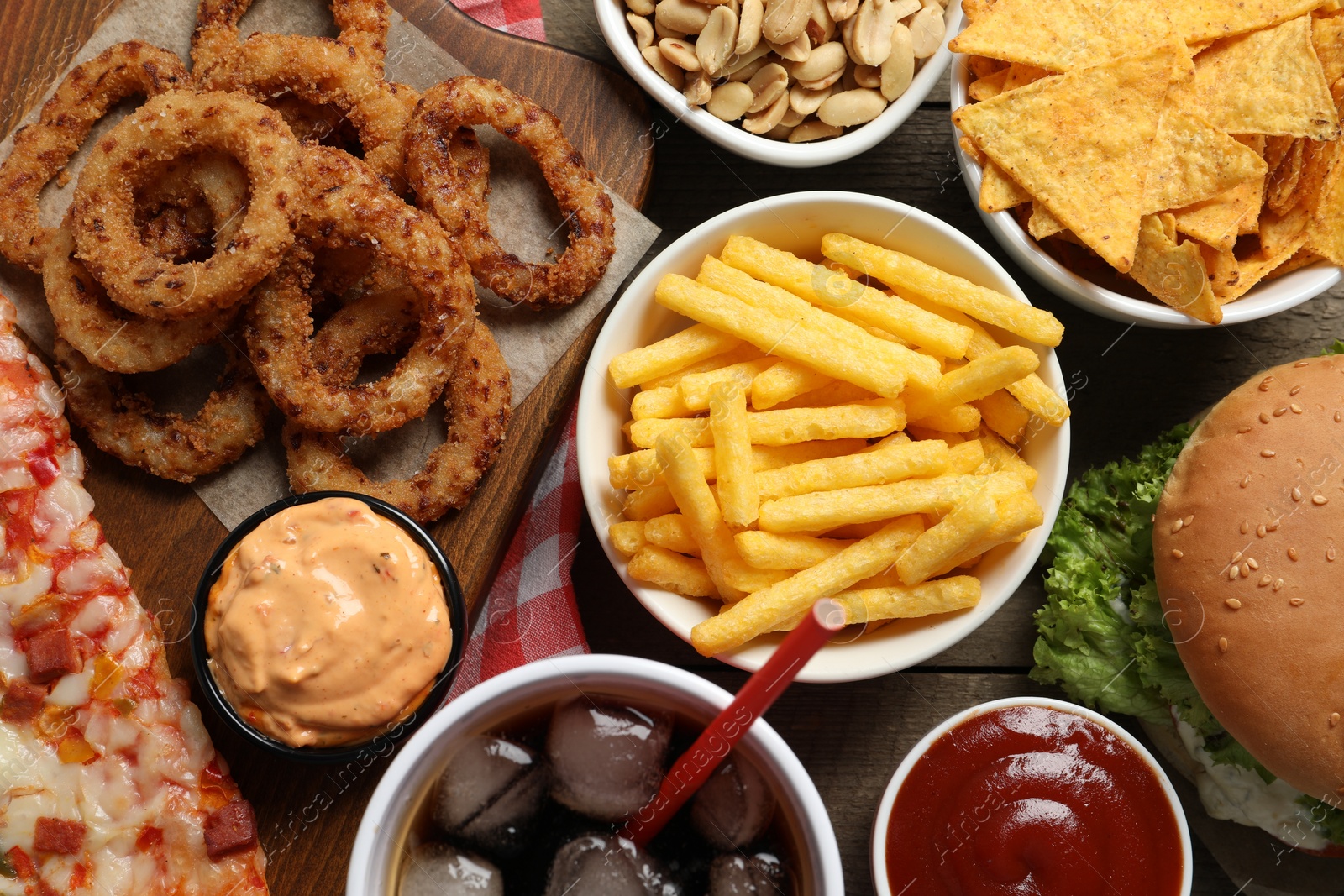 Photo of French fries, onion rings and other fast food on wooden table, flat lay