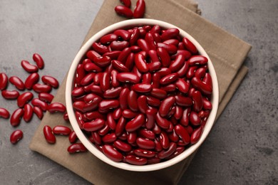 Raw red kidney beans in bowl and napkin on grey table, flat lay
