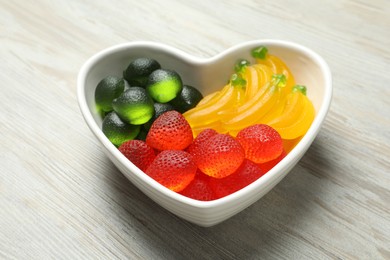 Photo of Delicious gummy fruit shaped candies on white wooden table