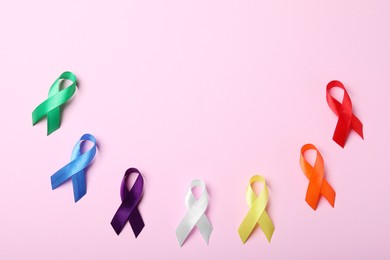 Colorful ribbons on pink background, flat lay with space for text. World Cancer Day