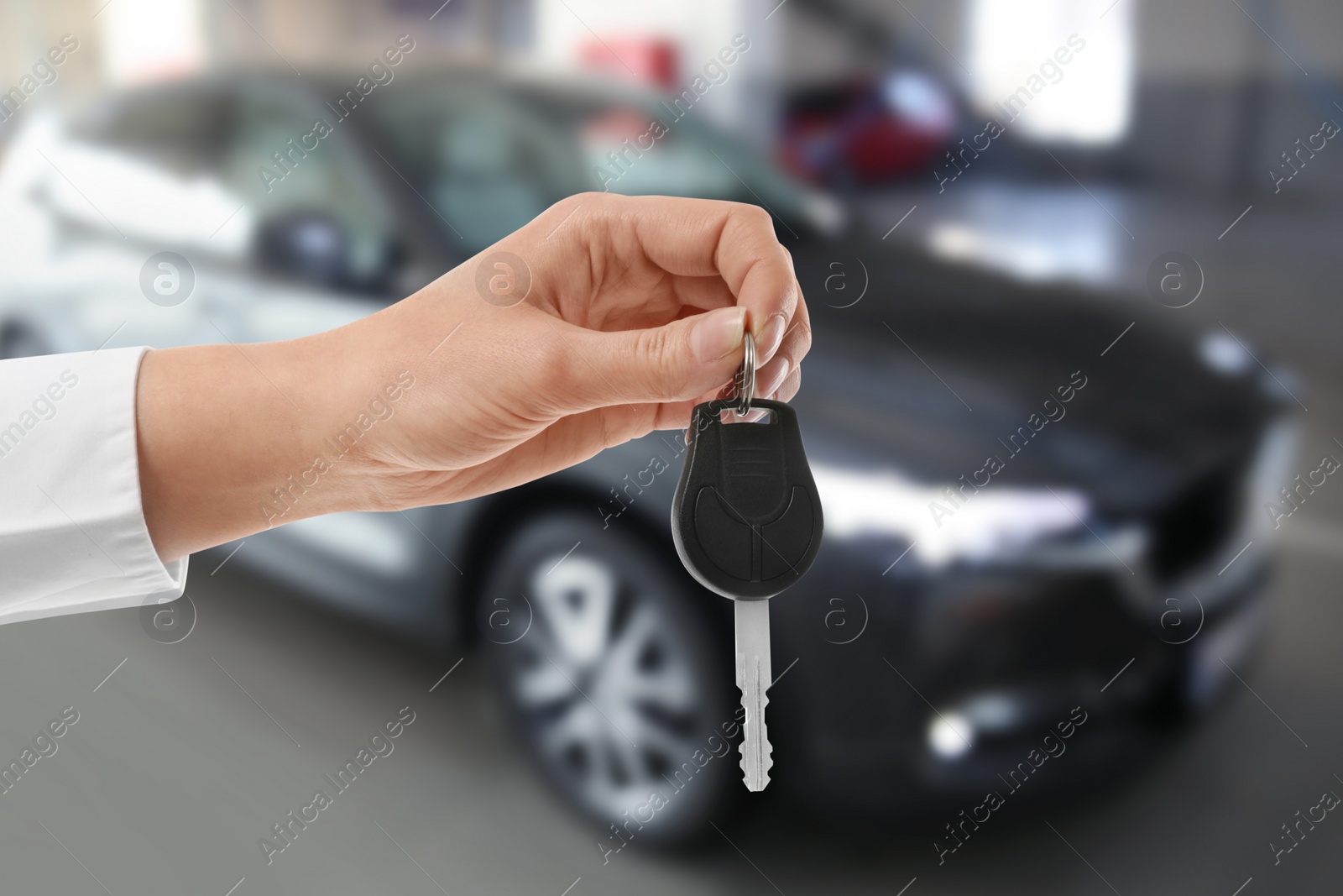 Image of Woman with key near new automobile indoors, closeup