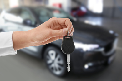 Image of Woman with key near new automobile indoors, closeup