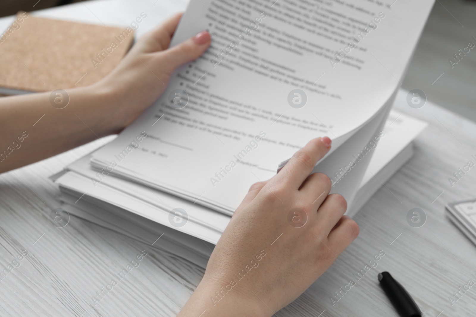 Photo of Woman reading documents at white wooden table in office, closeup