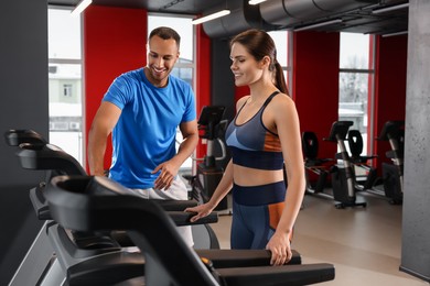 Photo of Happy trainer explaining woman how to do exercise properly in modern gym, space for text