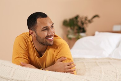 Photo of Portrait of smiling African American man on bed at home. Space for text