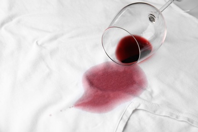 Photo of Overturned glass and spilled exquisite red wine on white t-shirt. Space for text