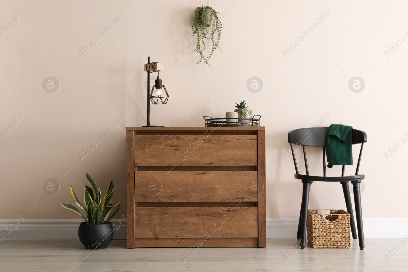 Photo of Room interior with wooden chest of drawers near beige wall