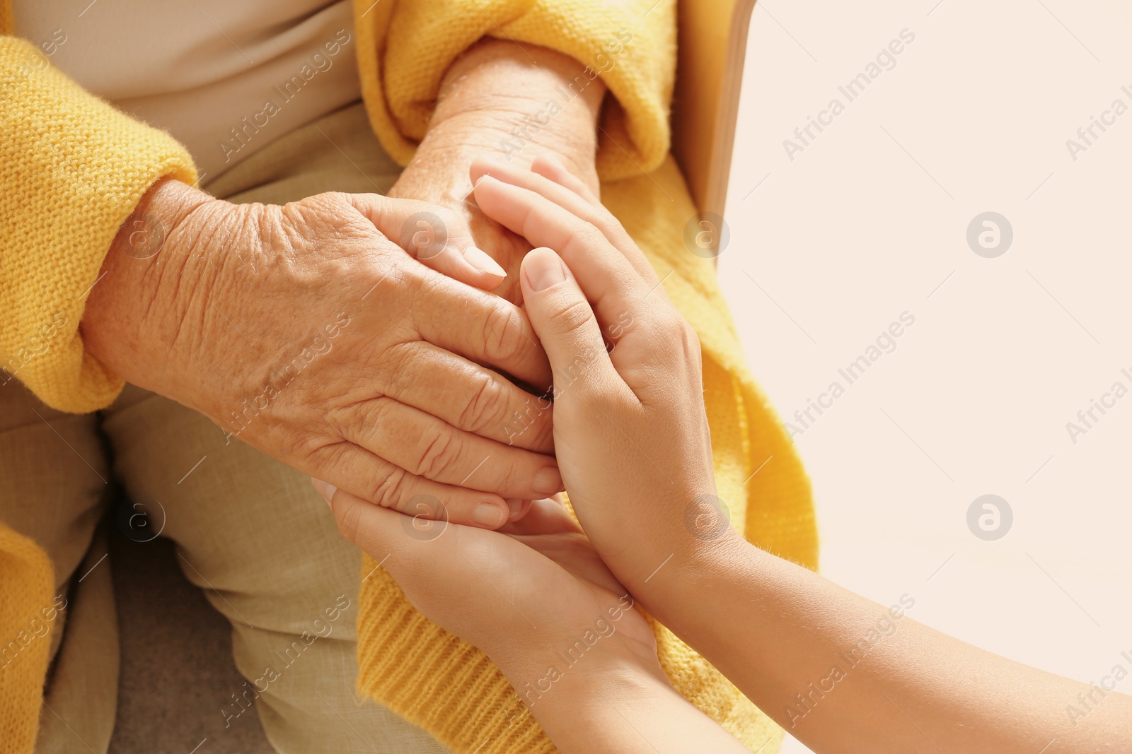 Photo of Helping hands on light background, closeup. Elderly care concept