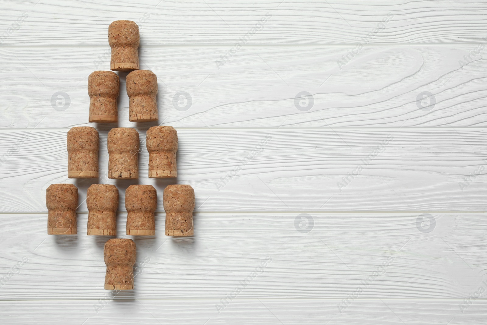 Photo of Christmas tree made of sparkling wine corks on white wooden table, top view. Space for text