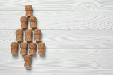 Photo of Christmas tree made of sparkling wine corks on white wooden table, top view. Space for text