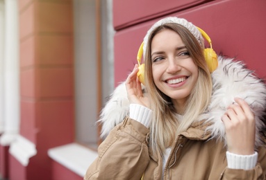 Photo of Young woman with headphones listening to music outdoors. Space for text