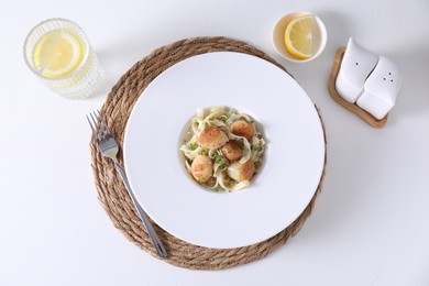 Delicious scallop pasta with spices in bowl served on white table, flat lay