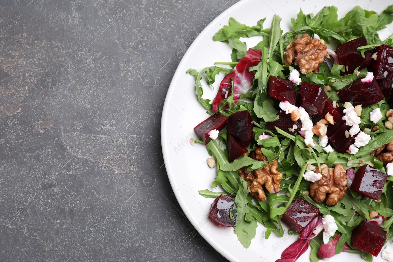 Photo of Delicious beet salad served on grey table, top view. Space for text