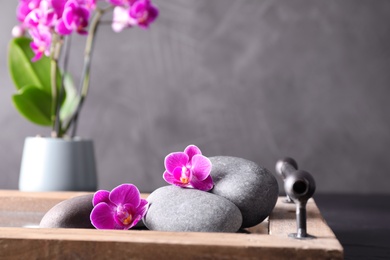 Photo of Composition with orchid flowers and spa stones on tray against grey background