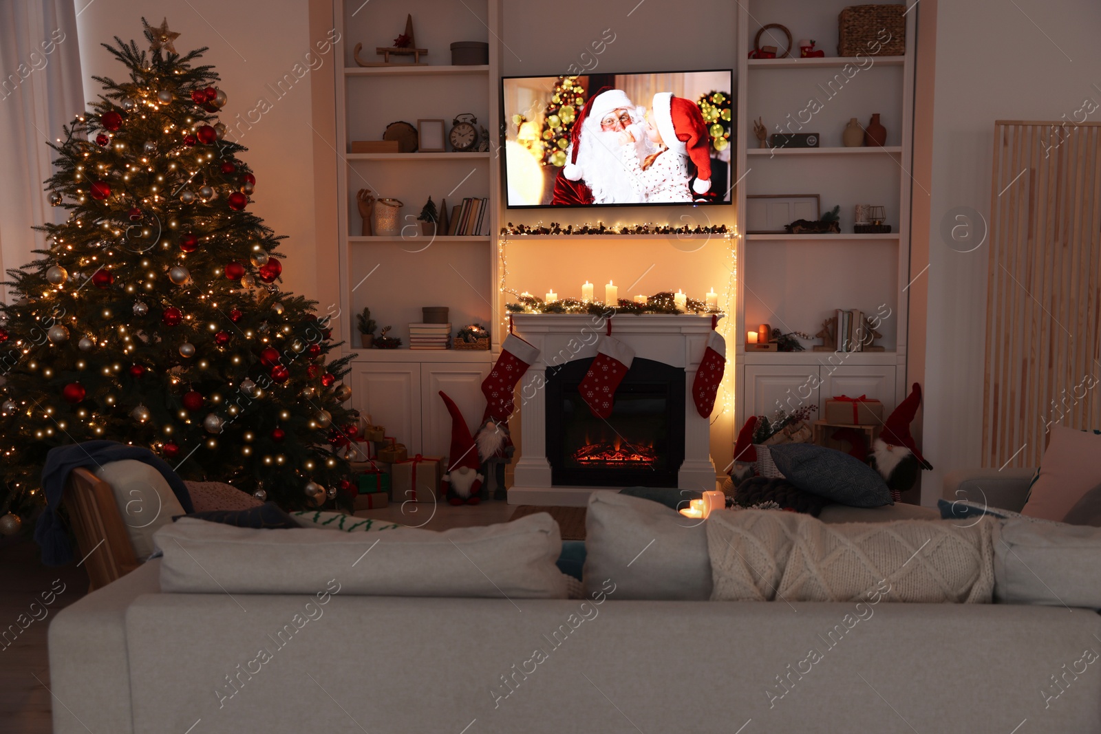 Photo of TV set with Christmas movie above fireplace in cosy room. Winter holidays atmosphere