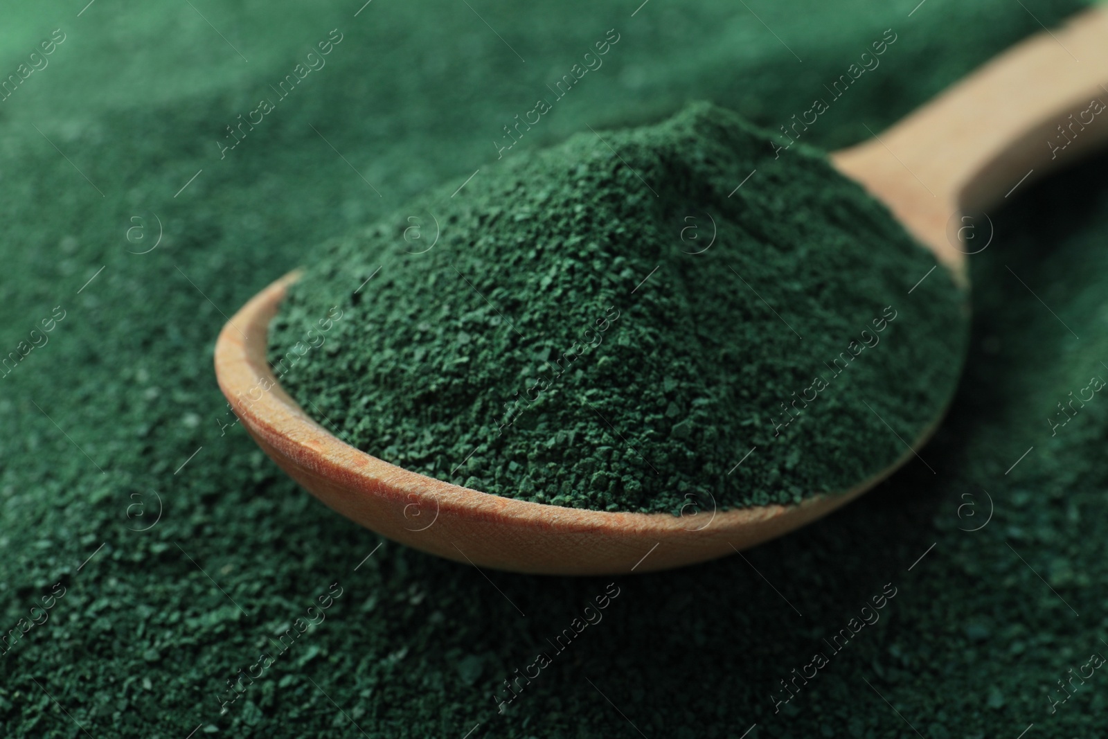 Photo of Spoon of spirulina on green algae powder, closeup