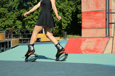 Photo of Woman doing exercises in kangoo jumping boots in workout park, closeup
