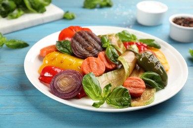 Photo of Delicious grilled vegetables with basil on light blue wooden table, closeup