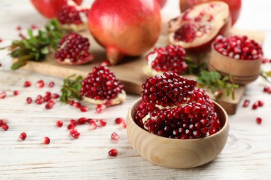 Photo of Delicious ripe pomegranate kernels in bowl on white wooden table