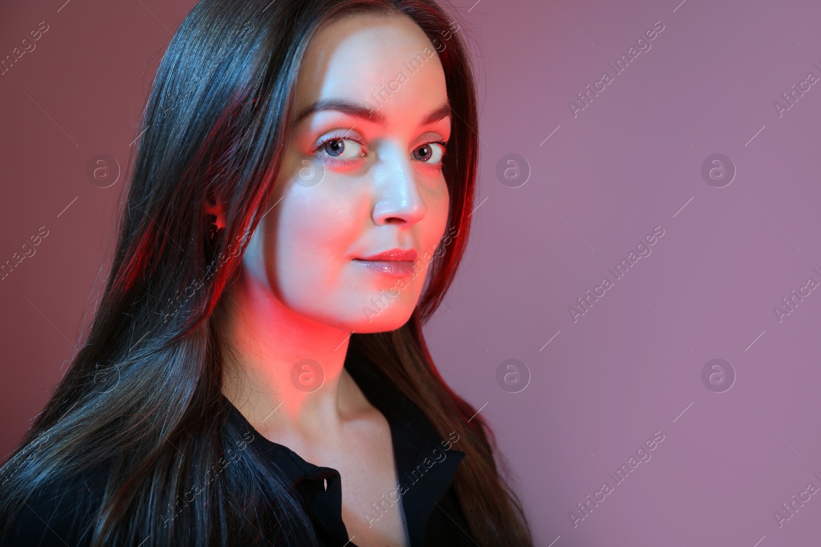 Photo of Portrait of beautiful young woman on color background with neon lights. Space for text