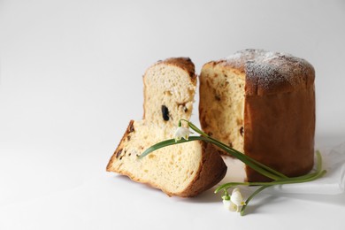 Photo of Delicious Panettone cake and beautiful flowers on white background. Traditional Italian pastry