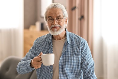 Photo of Portrait of happy grandpa with glasses and cup of drink indoors