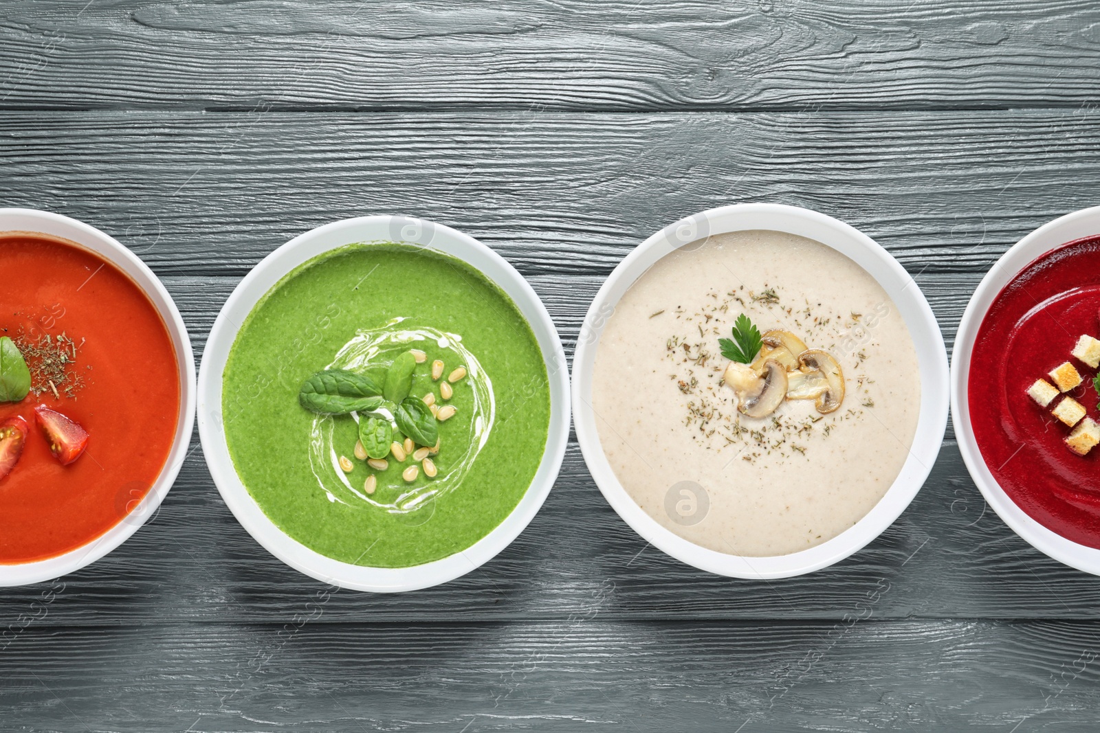 Photo of Various soups in bowls on wooden background, top view. Healthy food