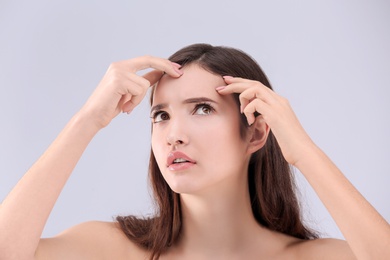 Teenage girl with acne problem against grey background