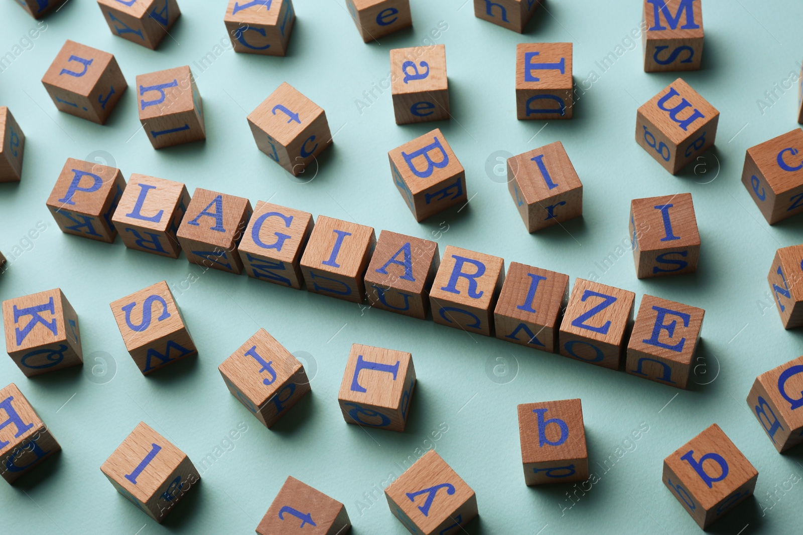 Photo of Wooden cubes with word Plagiarize on turquoise background, above view