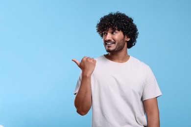 Handsome smiling man on light blue background, space for text