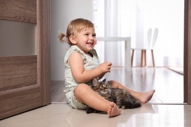 Cute little child with adorable pet on floor at home