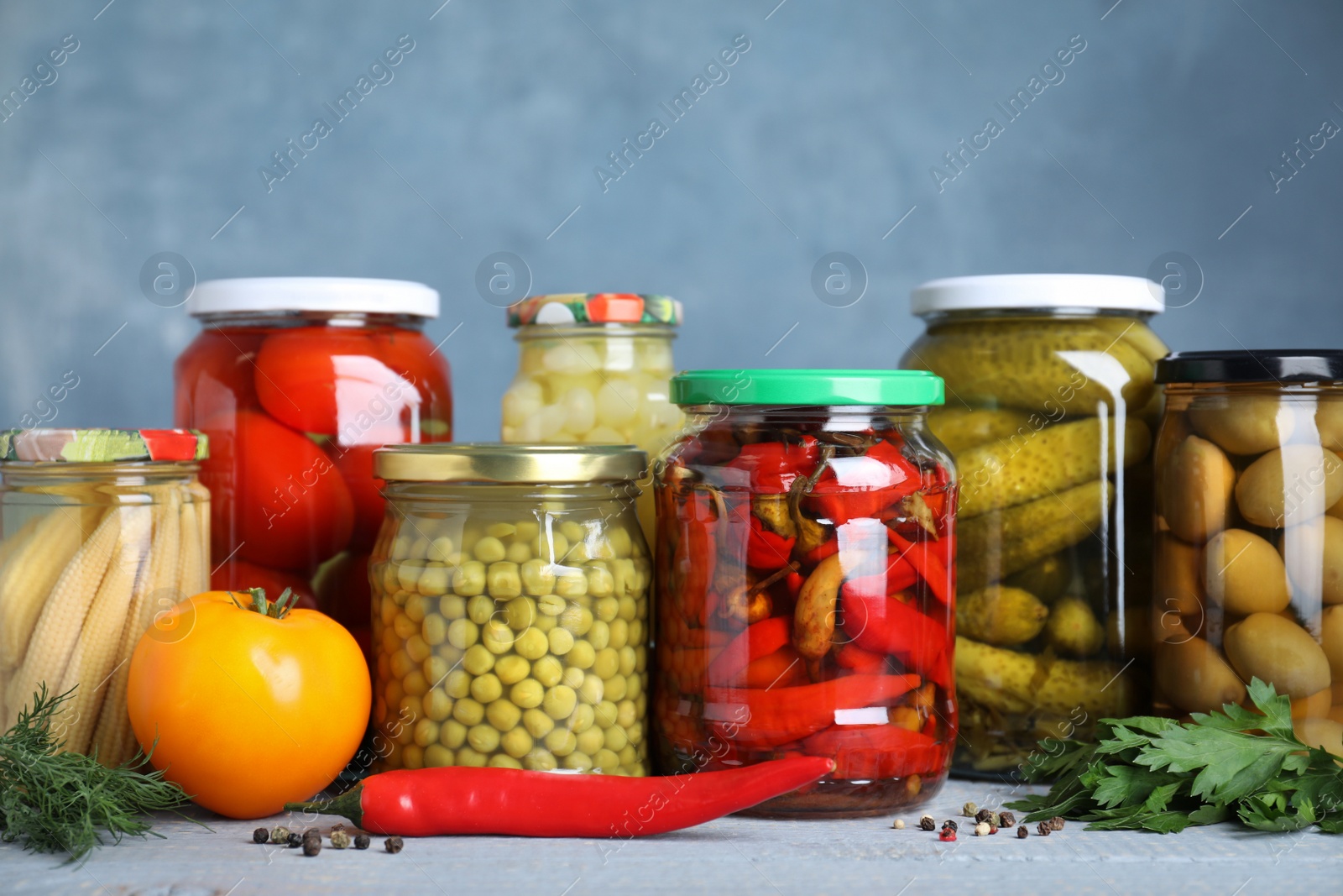 Photo of Glass jars with different pickled vegetables on table