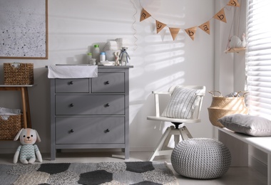 Photo of Chest of drawers with changing place in baby room. Interior design