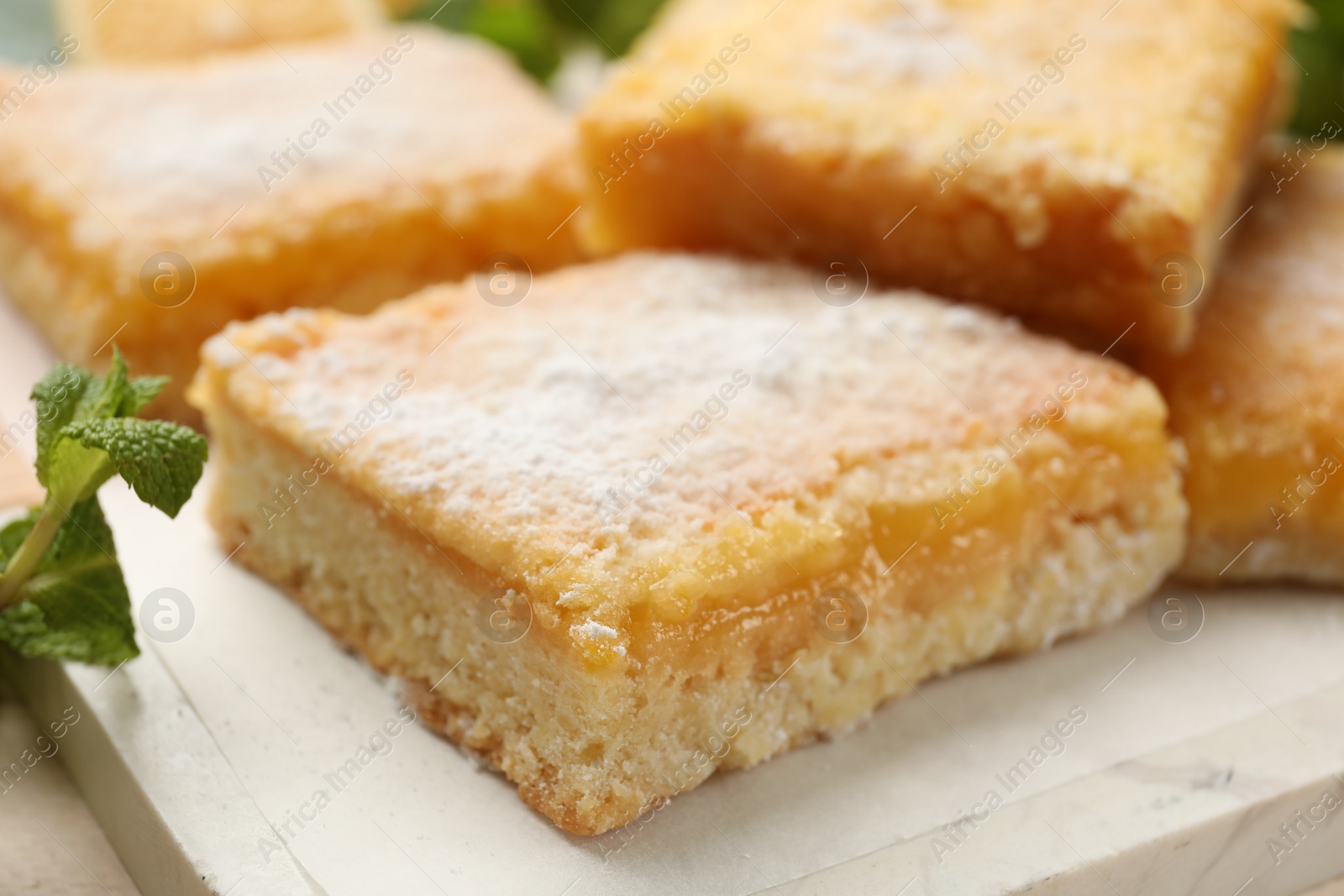 Photo of Tasty lemon bars with powdered sugar on table, closeup