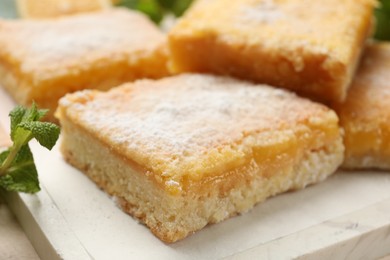 Tasty lemon bars with powdered sugar on table, closeup