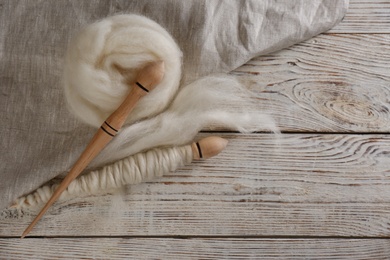 Soft wool and spindles on white wooden table, flat lay. Space for text