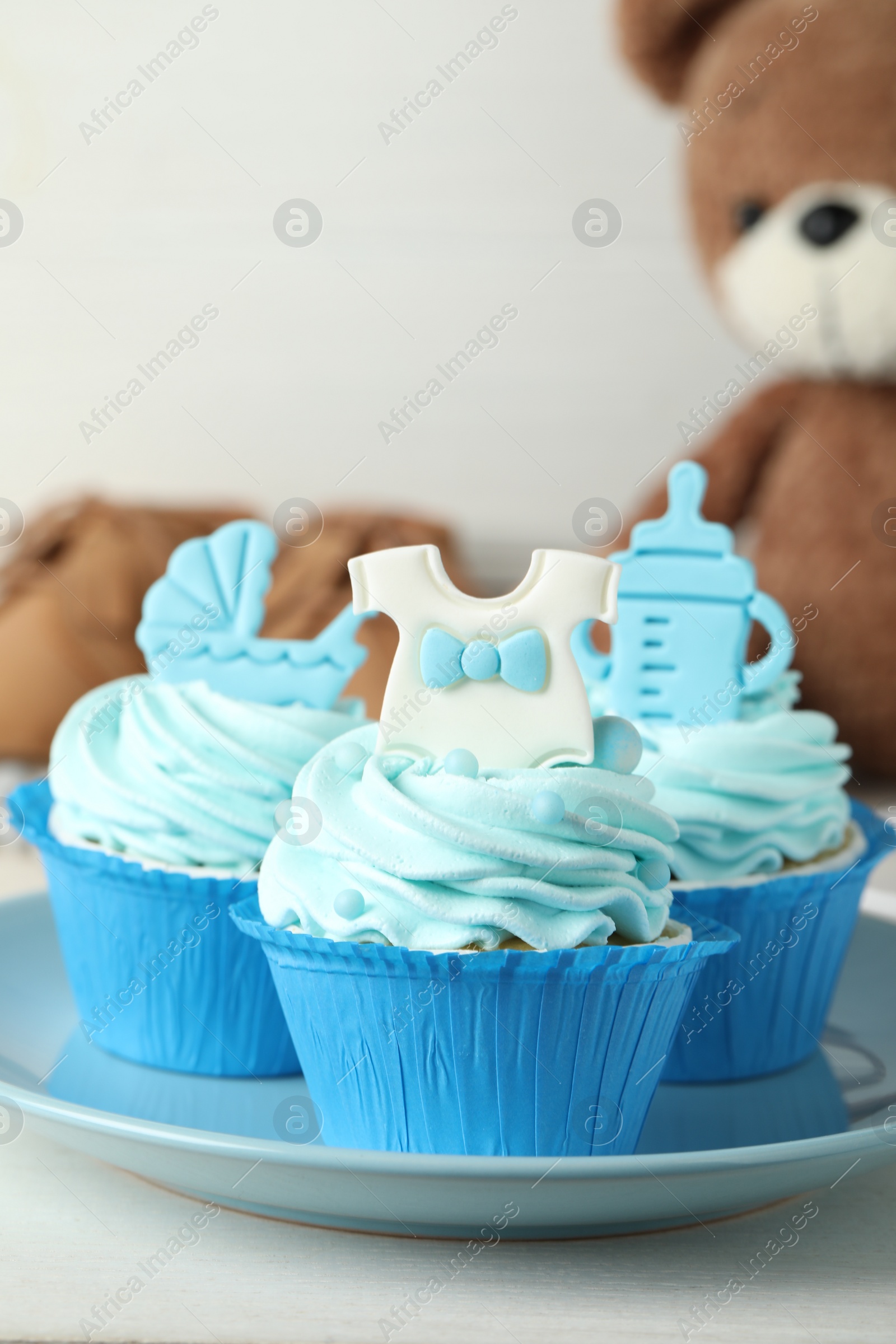 Photo of Beautifully decorated baby shower cupcakes for boy with cream and toppers on white table