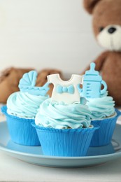 Photo of Beautifully decorated baby shower cupcakes for boy with cream and toppers on white table