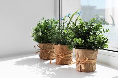 Artificial potted herbs on sunny day on windowsill indoors. Home decor