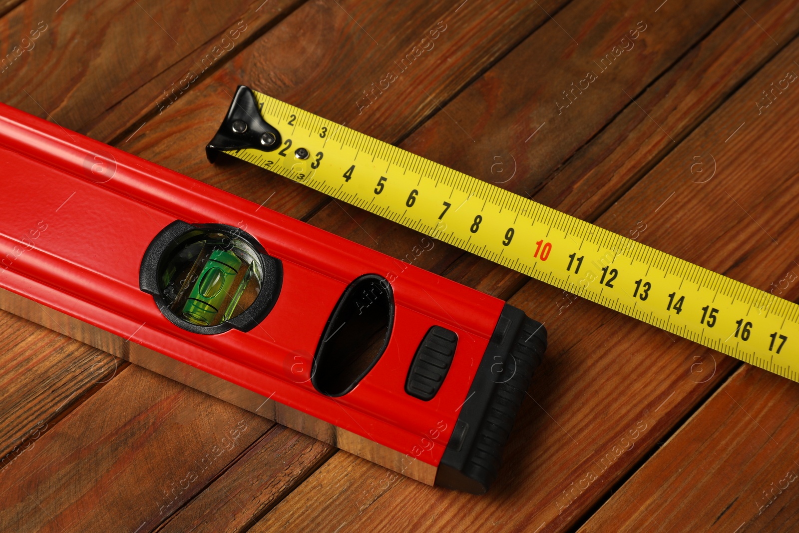 Photo of Building level and tape measure on wooden table, closeup