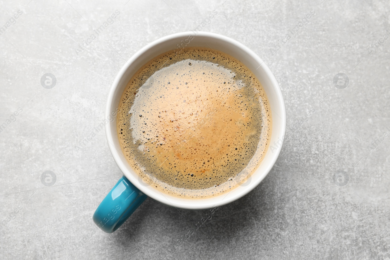 Photo of Cup of aromatic coffee on light grey table, top view