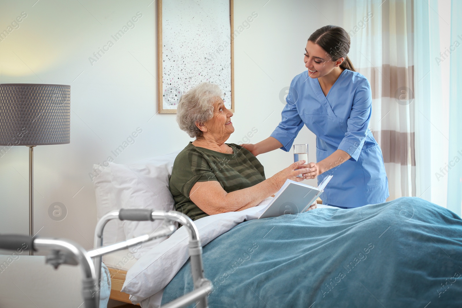 Photo of Care worker giving water to elderly woman in geriatric hospice