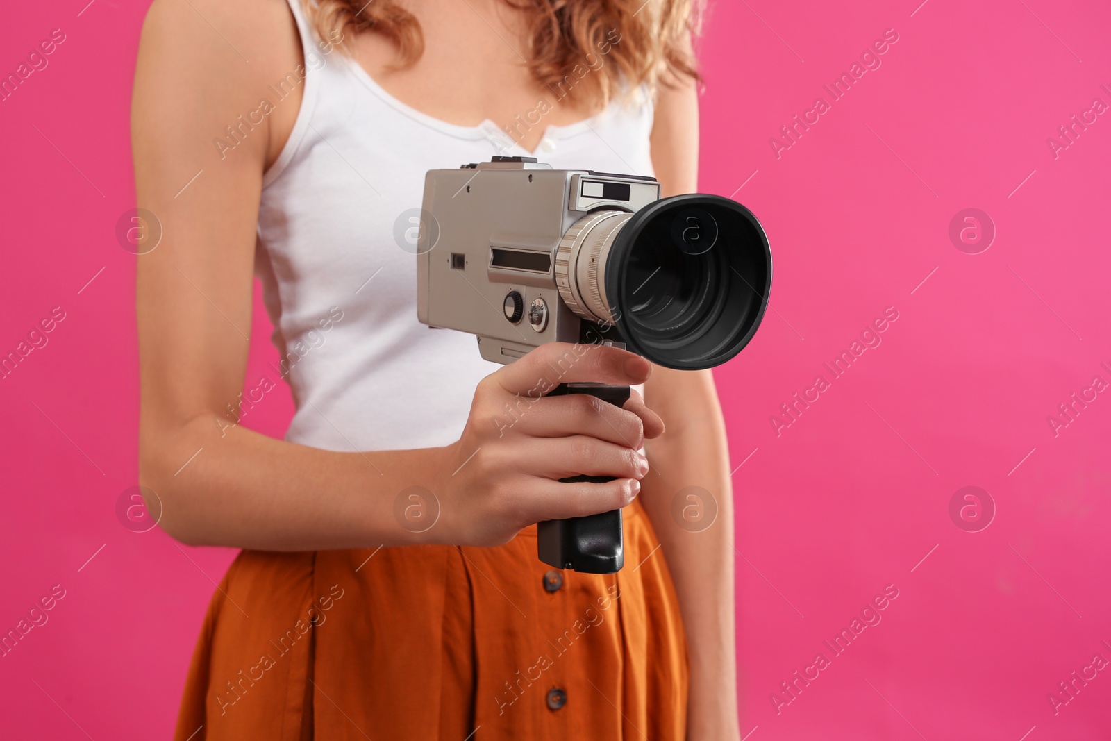 Photo of Woman with vintage video camera on crimson background, closeup