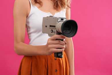 Photo of Woman with vintage video camera on crimson background, closeup