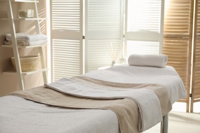 Photo of Massage table with soft towels in spa salon